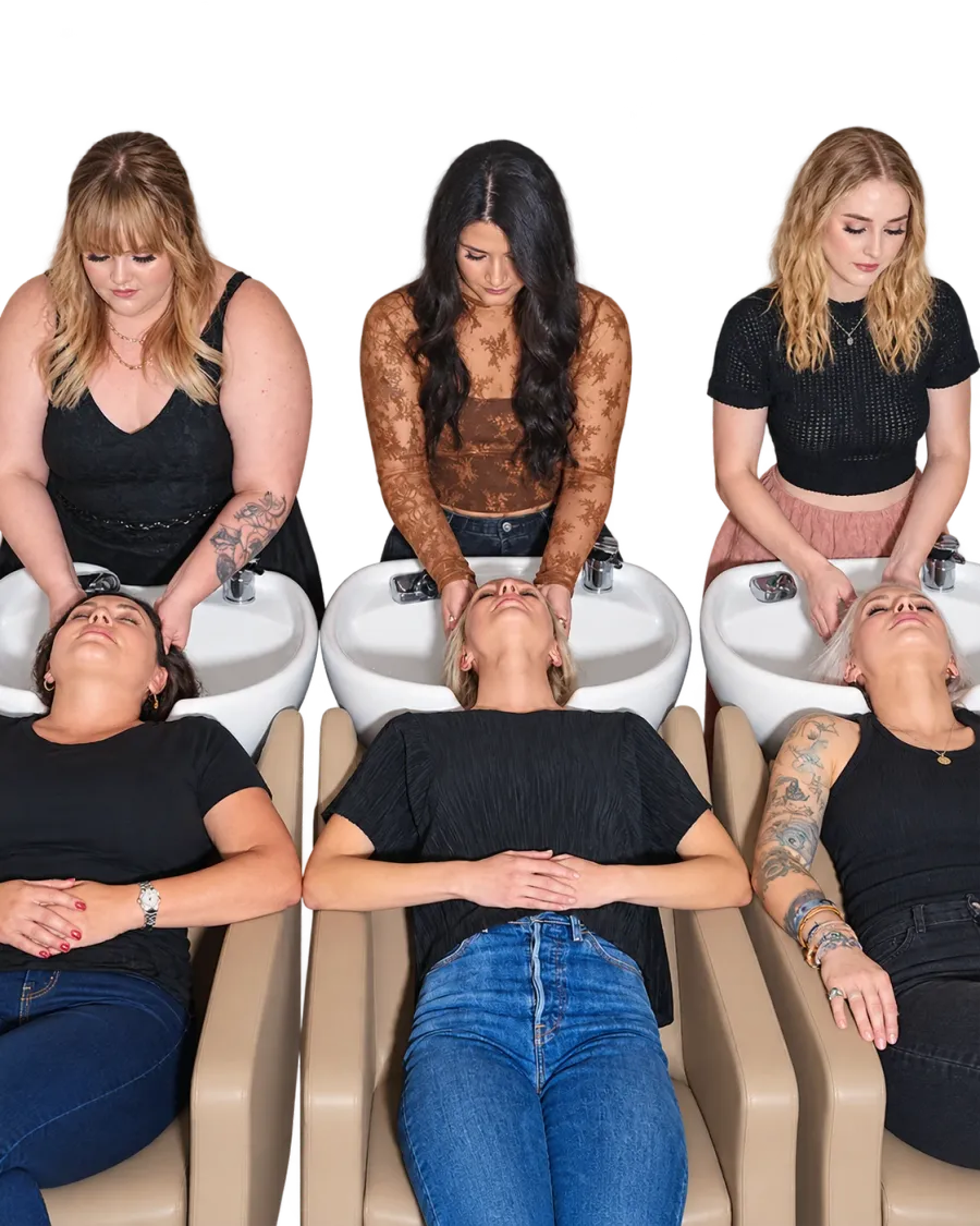 Three stylists washing their clients’ hair at the shampoo bowls.